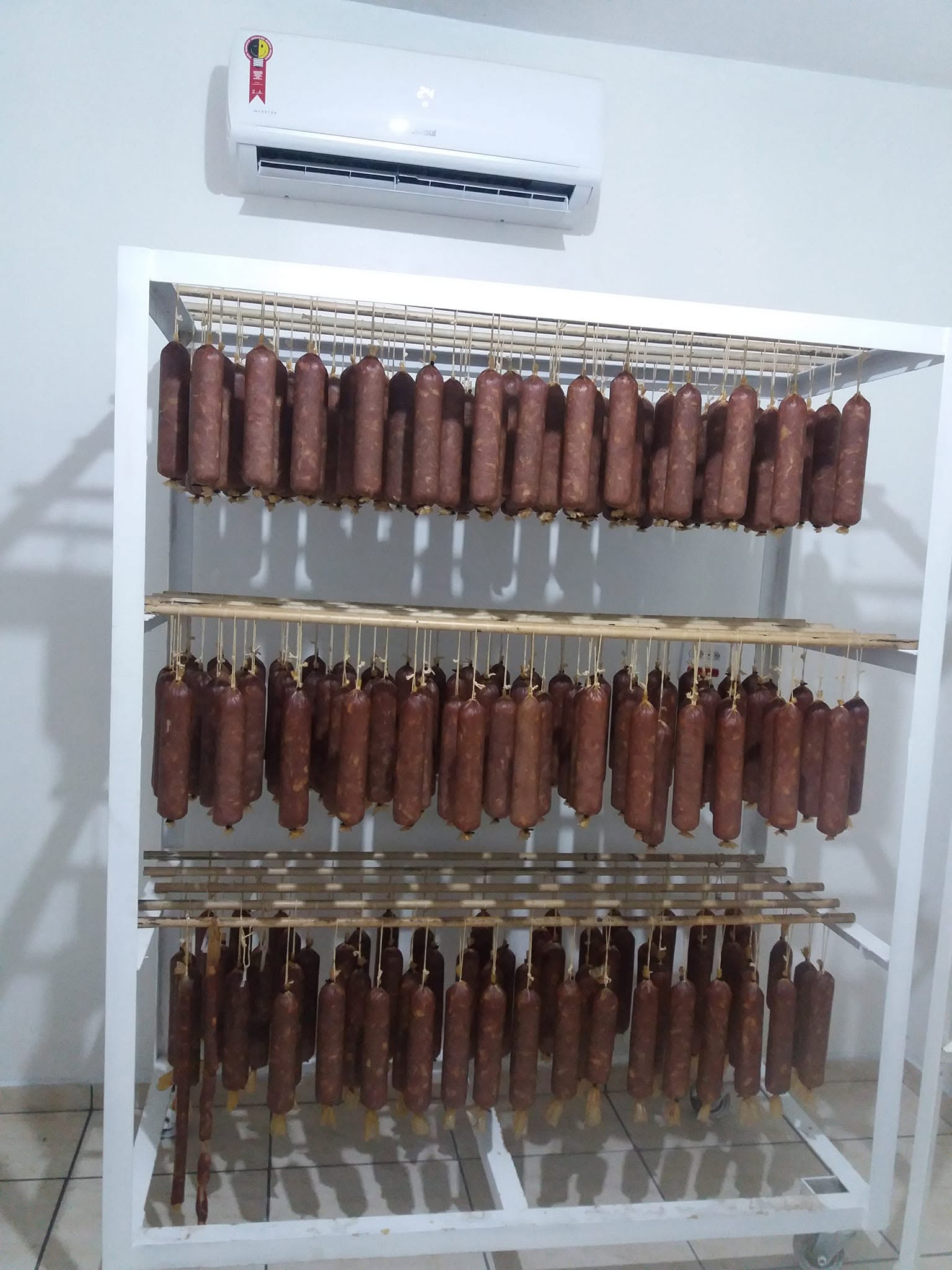 Câmara de cura artesanal da Lá da Roça, com salames pendurados para defumar